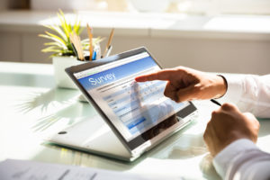 Businessman filling out online survey to give feedback on his tablet in office